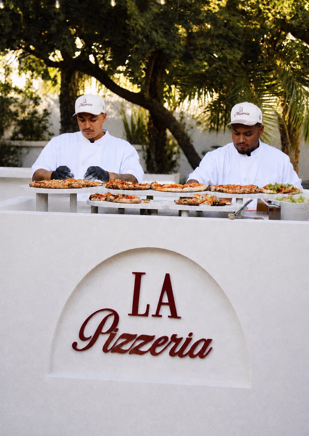La Pizzeria chefs serving fresh wood-fired pizza at a private event